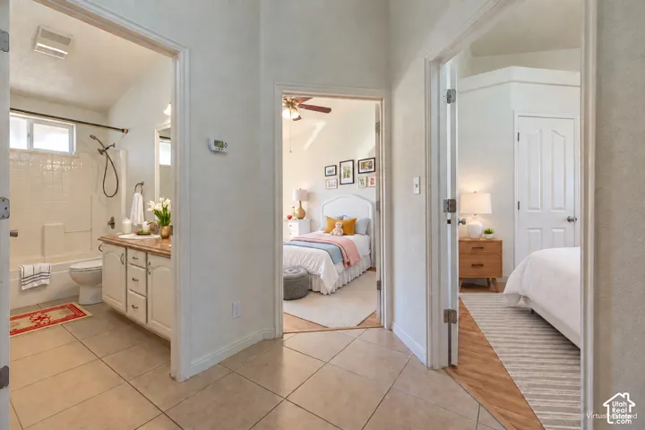 Bathroom featuring a combination tub and shower, a white vanity with cabinetry, and light-toned tile flooring
