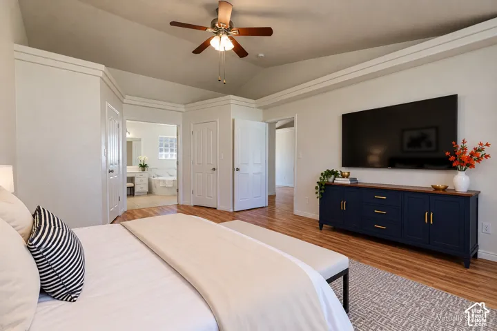 Vaulted ceilings with crown molding, wood-finish flooring, and a central ceiling fan fixture