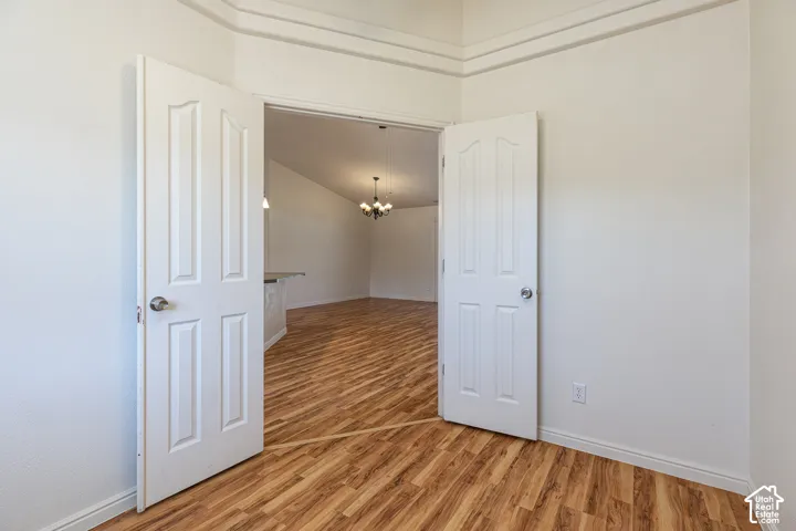 Double-door entry featuring four-panel doors, neutral wall finish, wood-finish flooring, and crown molding