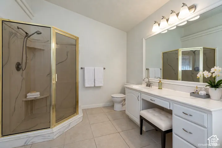 Corner shower with gold-tone frame, expansive vanity with white cabinetry, solid-surface countertop, full-width wall mirror, and four-bulb overhead lighting fixture