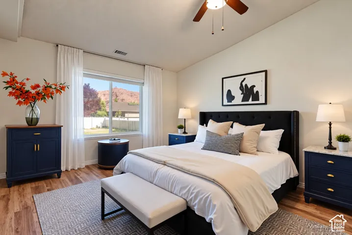 Wood-finish flooring, large window, ceiling fan, and prominent red rock scenery