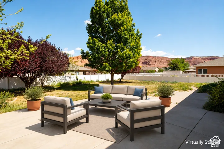 Concrete patio featuring a fenced backyard, mature trees, and a mountain backdrop