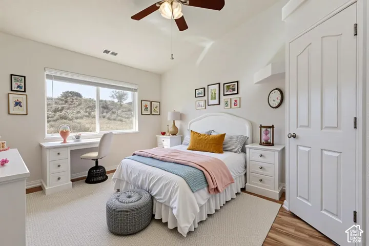 Room featuring a vaulted ceiling, ceiling fan with integrated lighting, a built-in desk with cabinetry, a large window, and a four-panel interior door