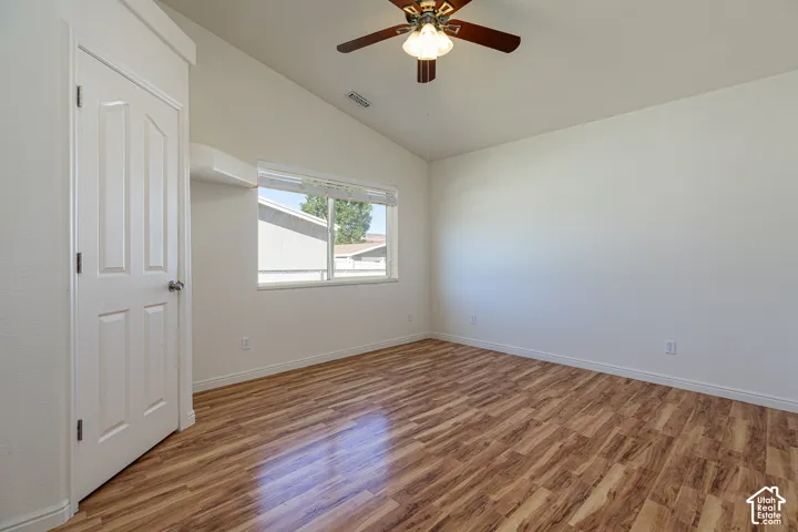 Vaulted ceilings, wood-finish flooring, central ceiling fan with integrated light fixture, and horizontal slider window