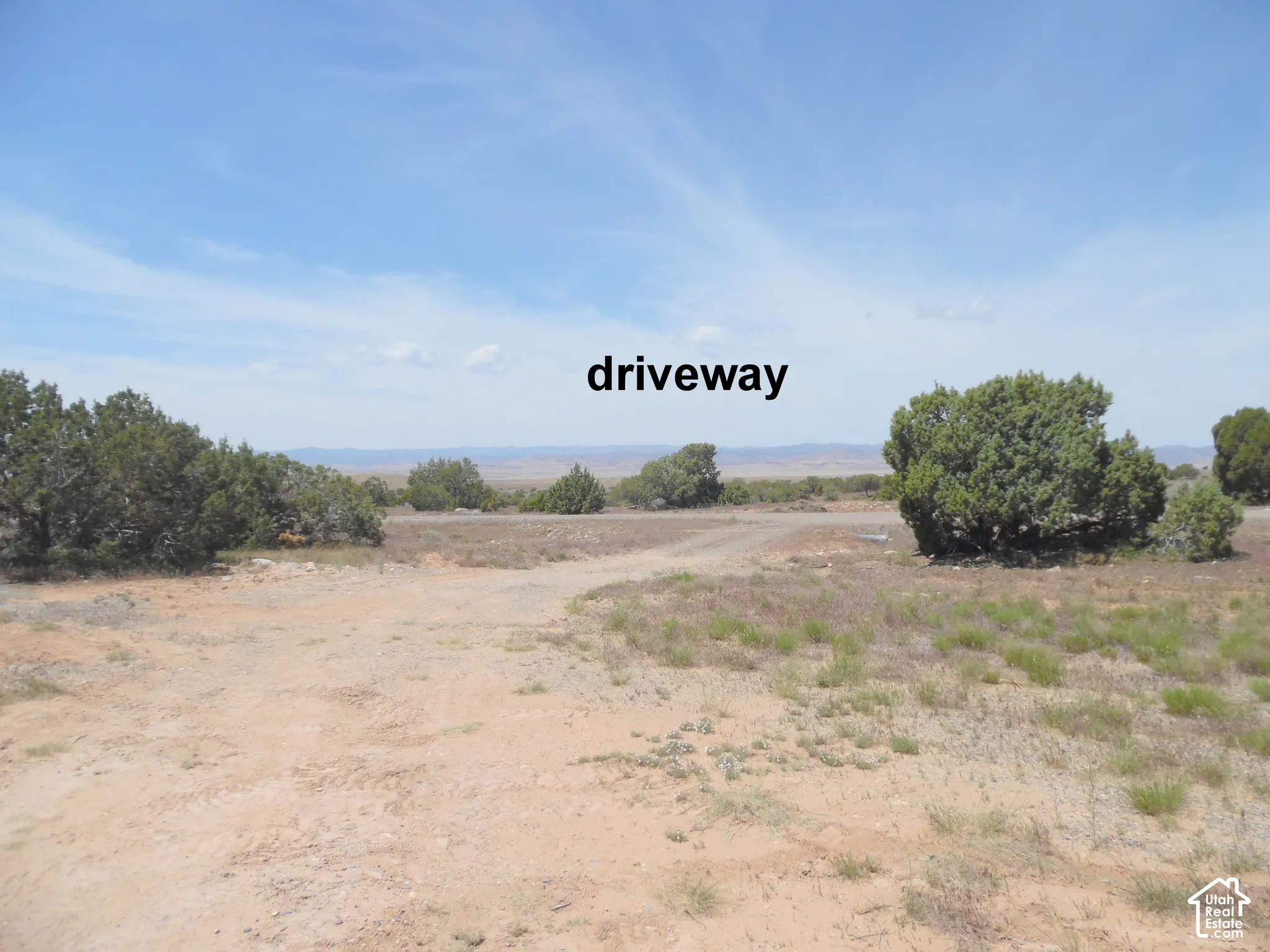 Unimproved lot featuring native desert vegetation, gravel driveway access, and mountain range backdrop