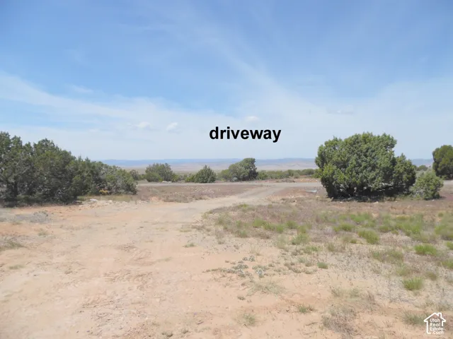 Unimproved lot featuring native desert vegetation, gravel driveway access, and mountain range backdrop