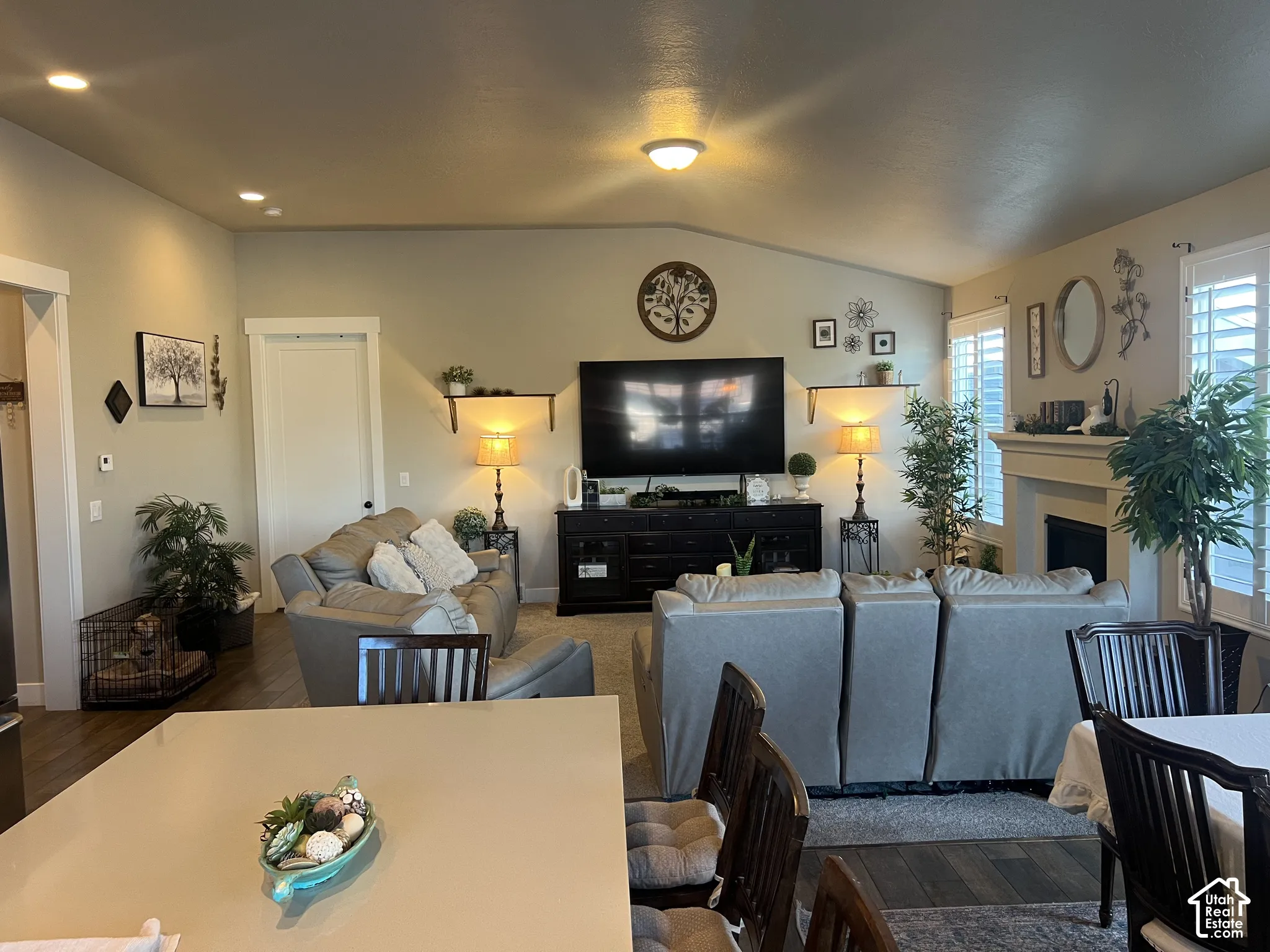 Open-concept interior featuring vaulted ceilings, recessed lighting, a fireplace with a mantel, and plantation shutters