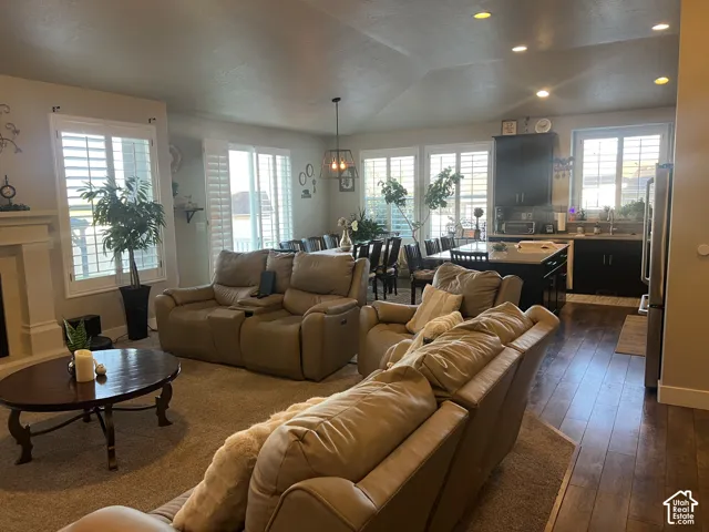 Open-concept living space featuring wood-finish flooring, recessed lighting, plantation shutters, dark-toned cabinetry, and a kitchen island