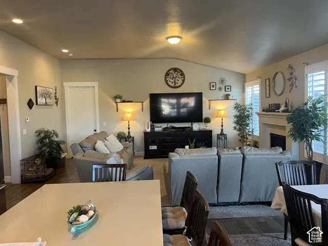 Open-concept interior featuring vaulted ceilings, recessed lighting, a fireplace with a mantel, and plantation shutters