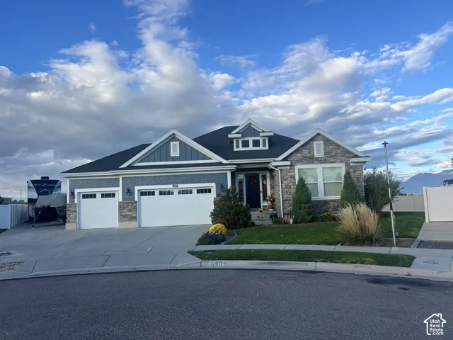Exterior featuring stone veneer and vertical siding, a three-car garage, multiple gables, and a manicured front lawn