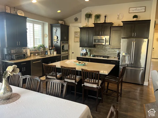 Kitchen featuring dark-finish cabinetry, an expansive center island with stone-surface countertop, recessed lighting, wood-finish flooring, and stainless steel built-in appliances