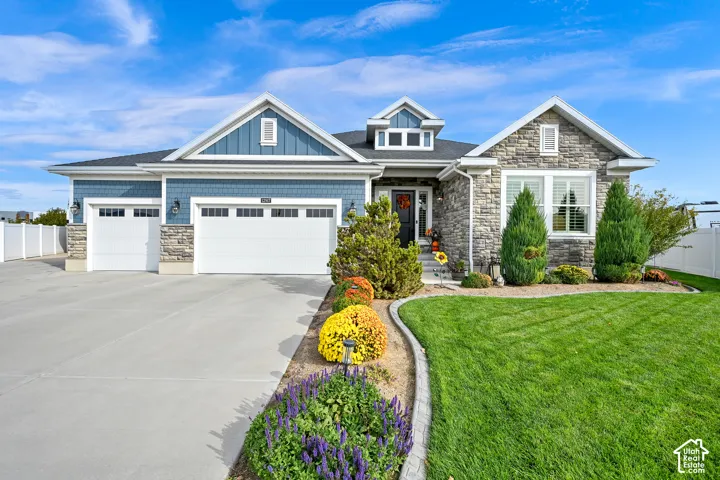 Exterior featuring a stone and shingle-style facade, multi-gabled roofline, three-car garage, and concrete driveway