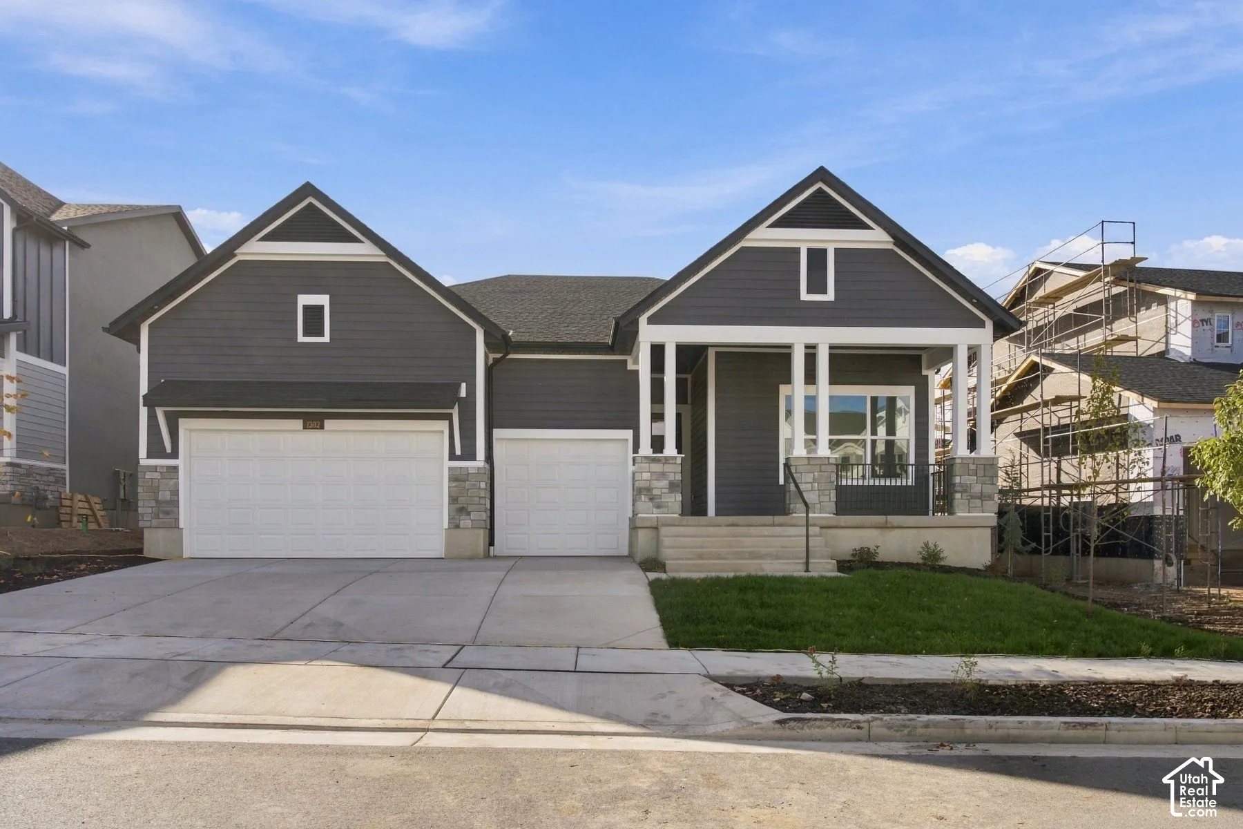 Exterior featuring dark horizontal siding, stone veneer accents, a covered front porch with white columns, and an attached three-car garage