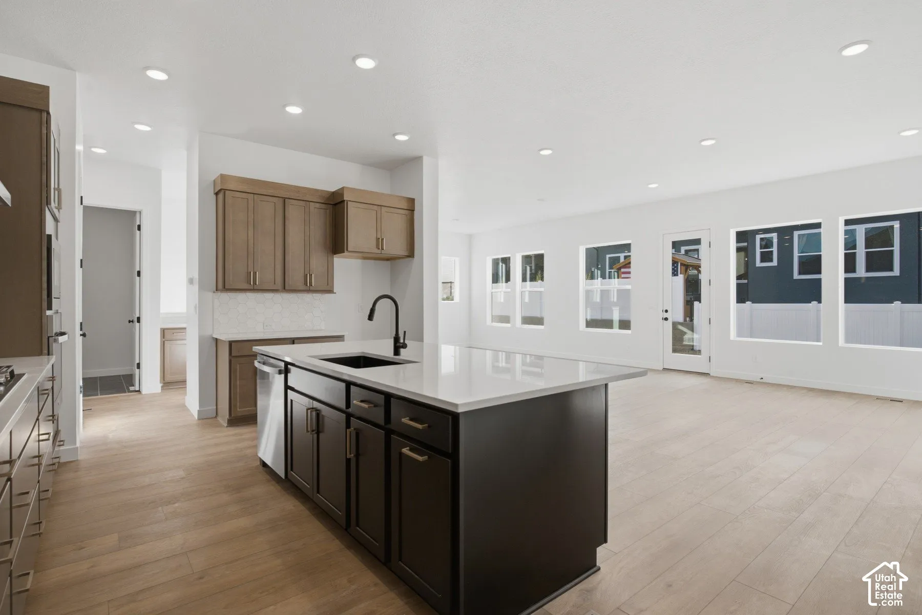 Kitchen featuring a center island with a stone-surface countertop, dark-finish cabinetry, recessed lighting, wood-finish flooring, and a matte black faucet