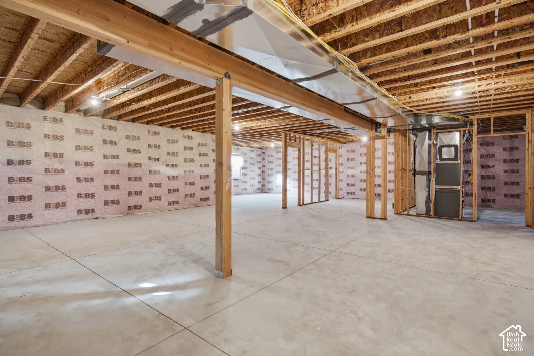 Unfinished lower level featuring concrete flooring, exposed wooden support beams, batt insulation, and exposed mechanical systems