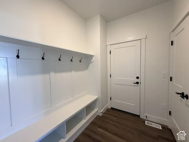 Built-in mudroom bench with integrated storage cubbies, white board-and-batten wall detailing, overhead shelving with wall-mounted hooks, solid-core shaker style doors, and wood-finish flooring