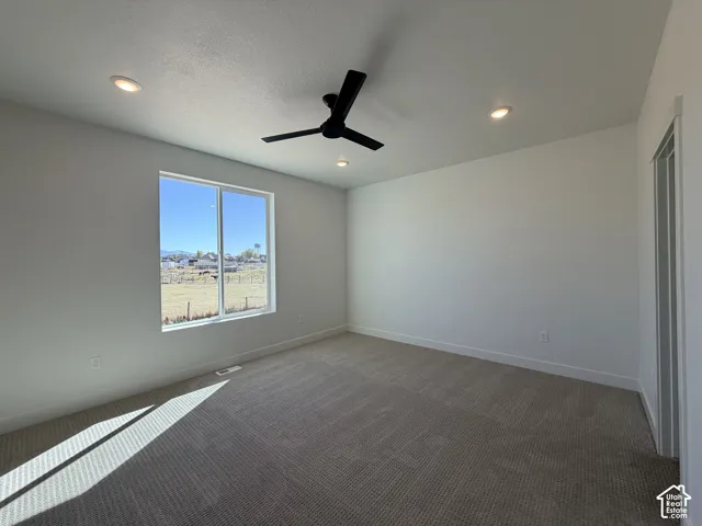 Neutral-toned wall-to-wall carpeting, matte black three-blade ceiling fan, recessed lighting, and a single-pane window