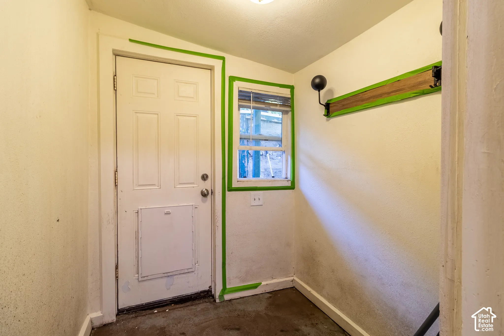 Entryway featuring a multi-panel door with an integrated pet door, a single-pane window, and wall-mounted hooks