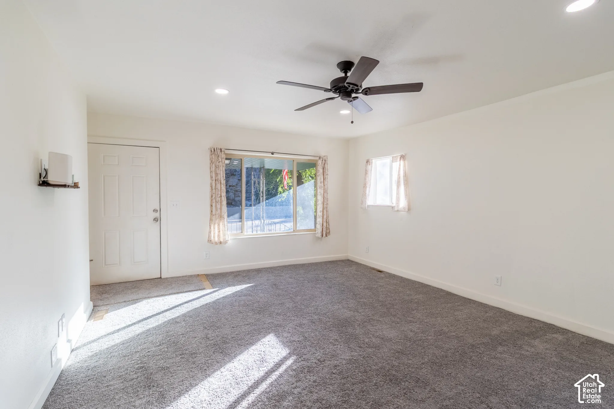 Interior space featuring neutral wall tones, wall-to-wall carpeting, recessed lighting, a ceiling fan, and large windows