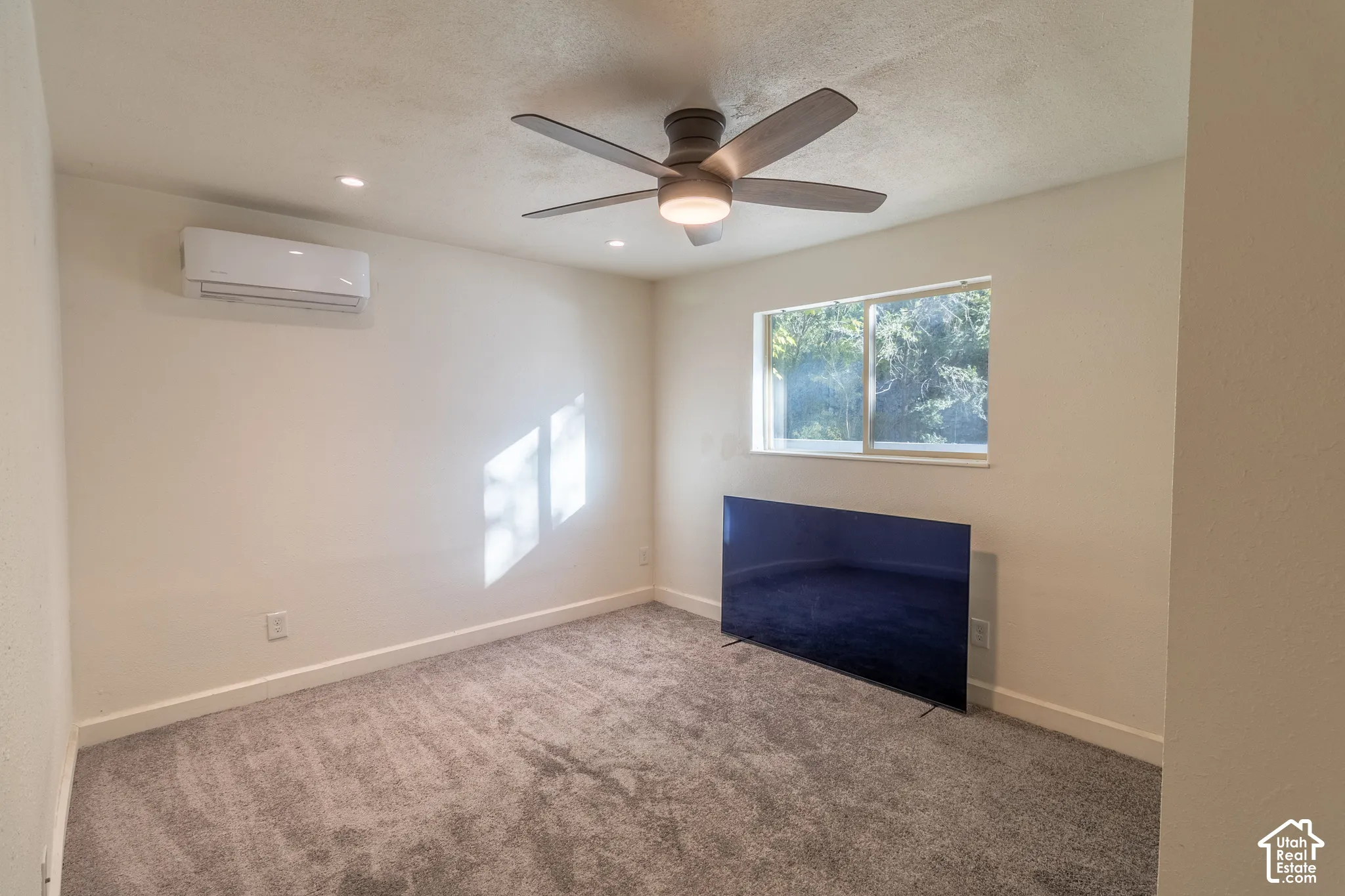 Wall-mounted ductless air conditioning unit, ceiling fan with integrated lighting, recessed lighting, and carpeted flooring