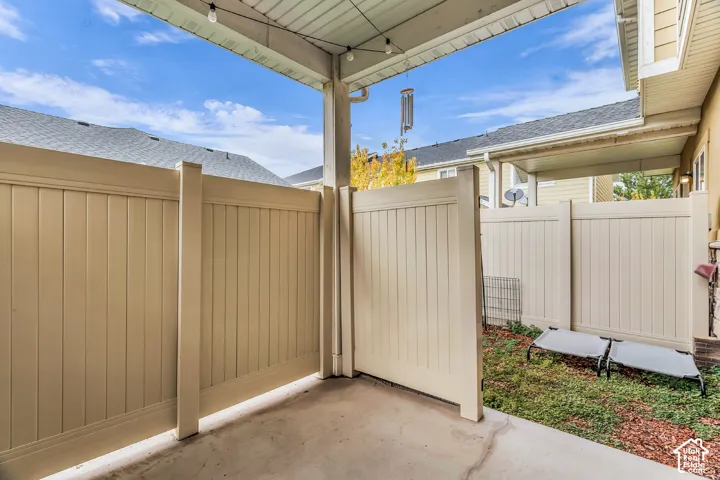 Covered concrete patio featuring a tall vinyl privacy fence and beadboard ceiling