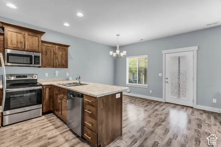 Kitchen featuring custom wood cabinetry, stone-finish countertops, stainless steel appliances, wood-finish flooring, and recessed lighting