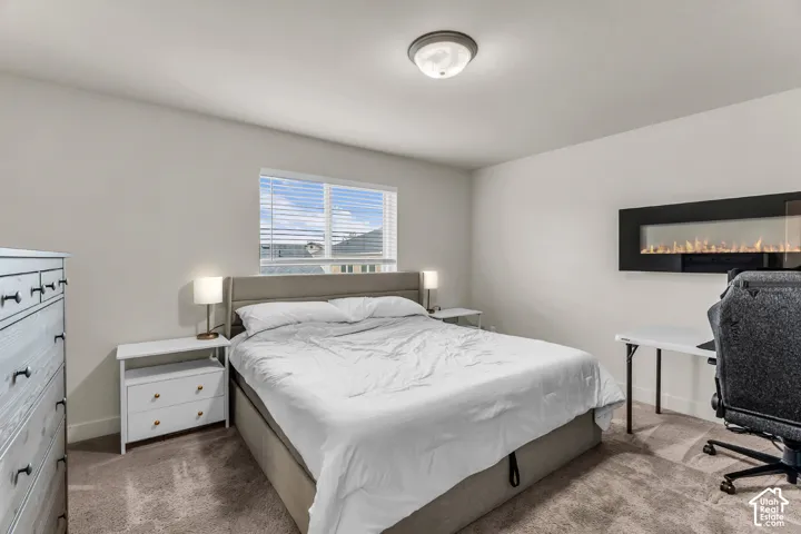 Wall-mounted electric fireplace, neutral wall tones, flush-mount lighting, and carpeted flooring