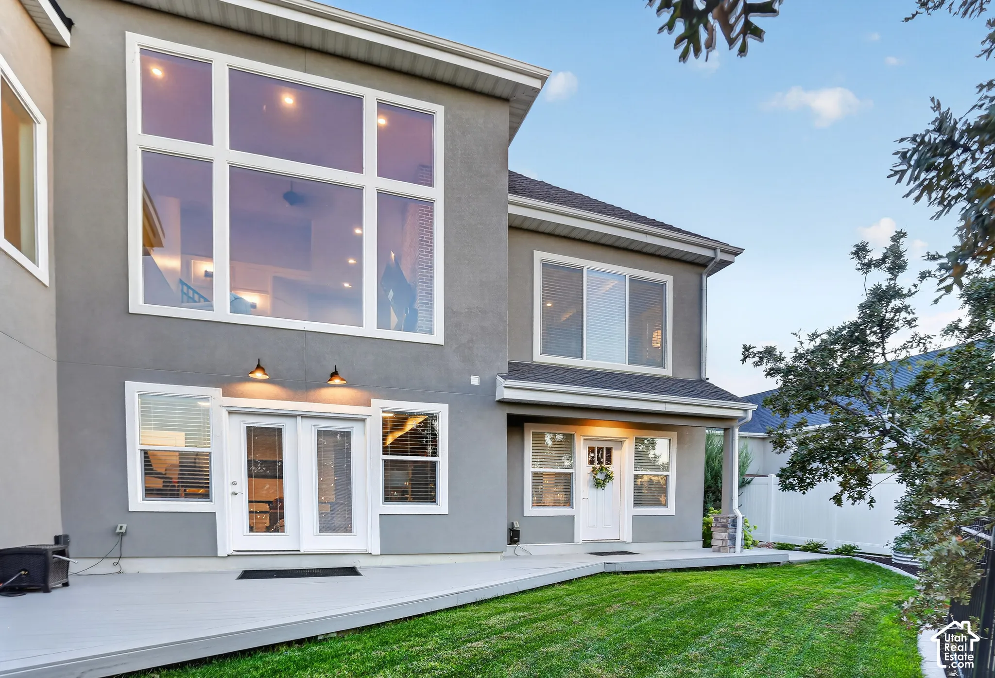 Stucco exterior with multi-level windows, large rear deck, and manicured lawn