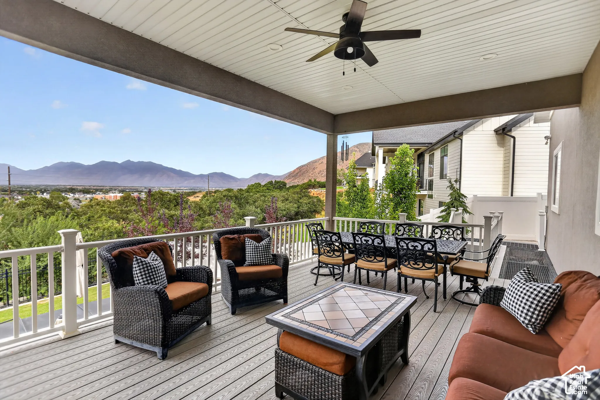 Covered deck featuring composite decking, white railing, ceiling fan, and mountain backdrop