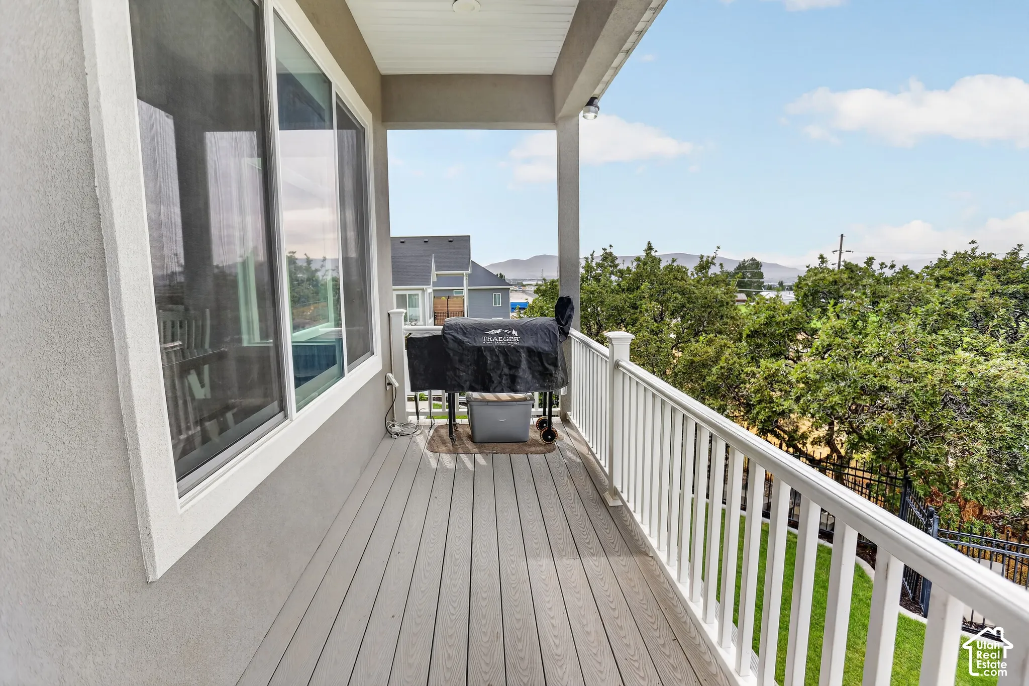 Covered balcony featuring composite decking, white picket railings, and mountainous terrain in the distance