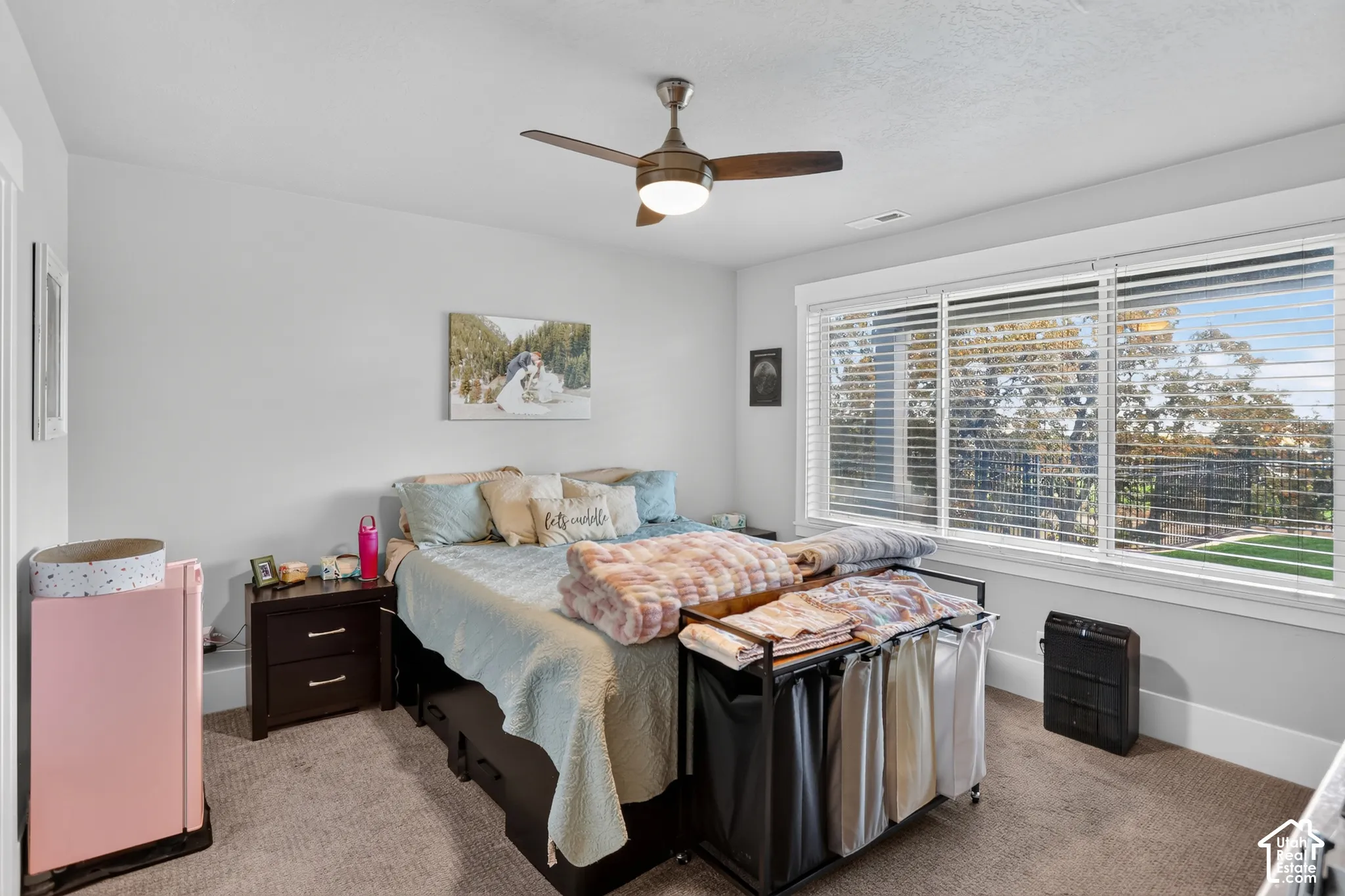 Neutral-toned carpeted flooring, large window with horizontal blinds, and ceiling fan with integrated lighting