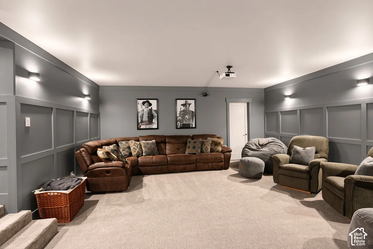 Interior room featuring extensive wall paneling, neutral carpeting, ceiling-mounted projection hardware, and multiple wall-mounted light fixtures