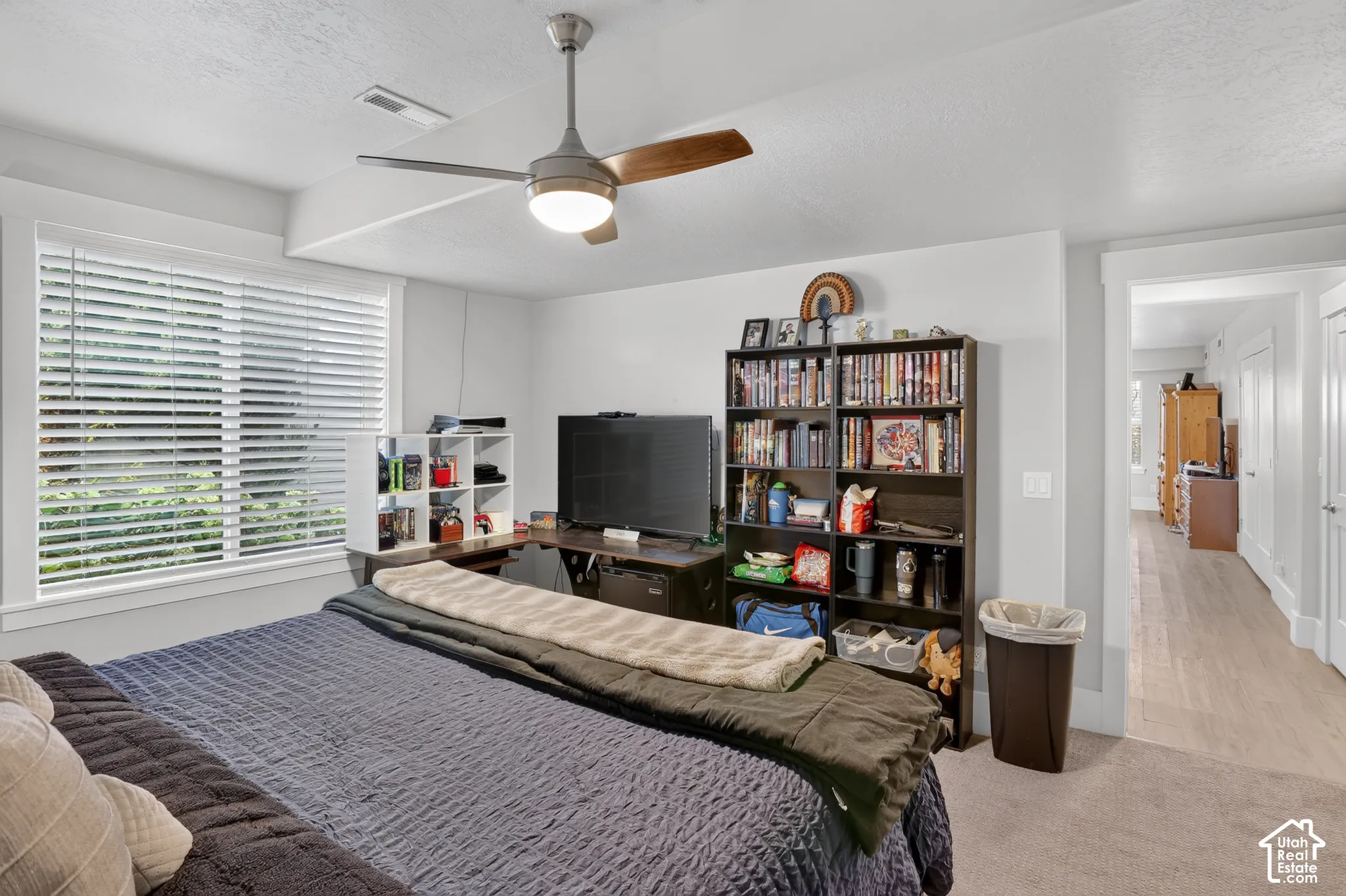 Bedroom featuring neutral wall paint, carpeted flooring, a ceiling fan with integrated lighting, and a window with horizontal blinds