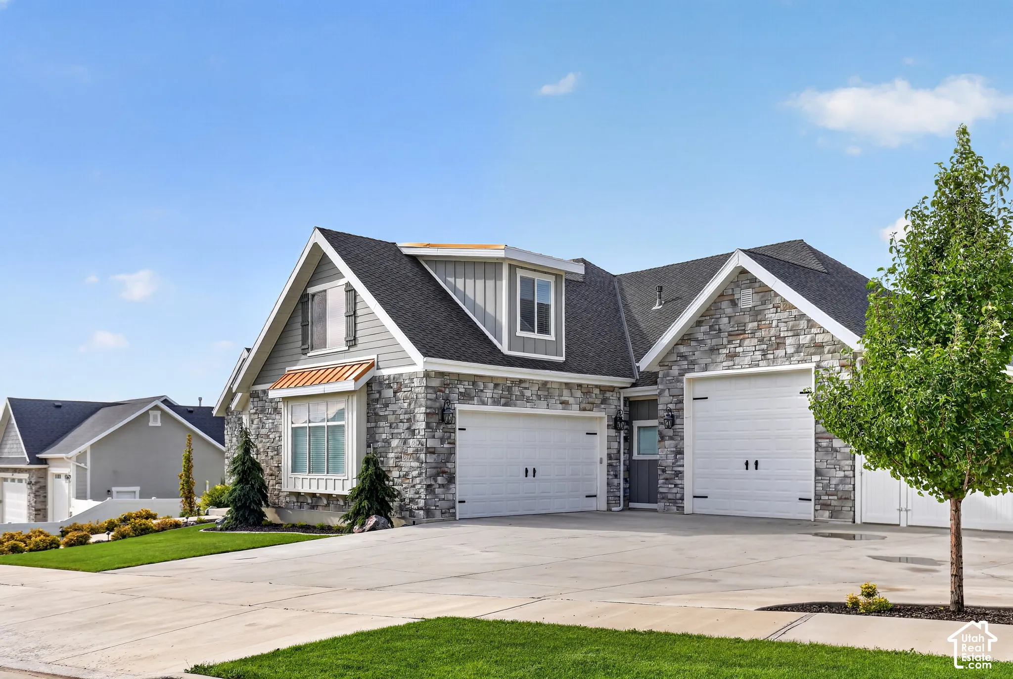 Exterior featuring a mixed-material facade of stone veneer and vertical siding, a multi-gabled roofline, an attached three-car garage, and a concrete driveway