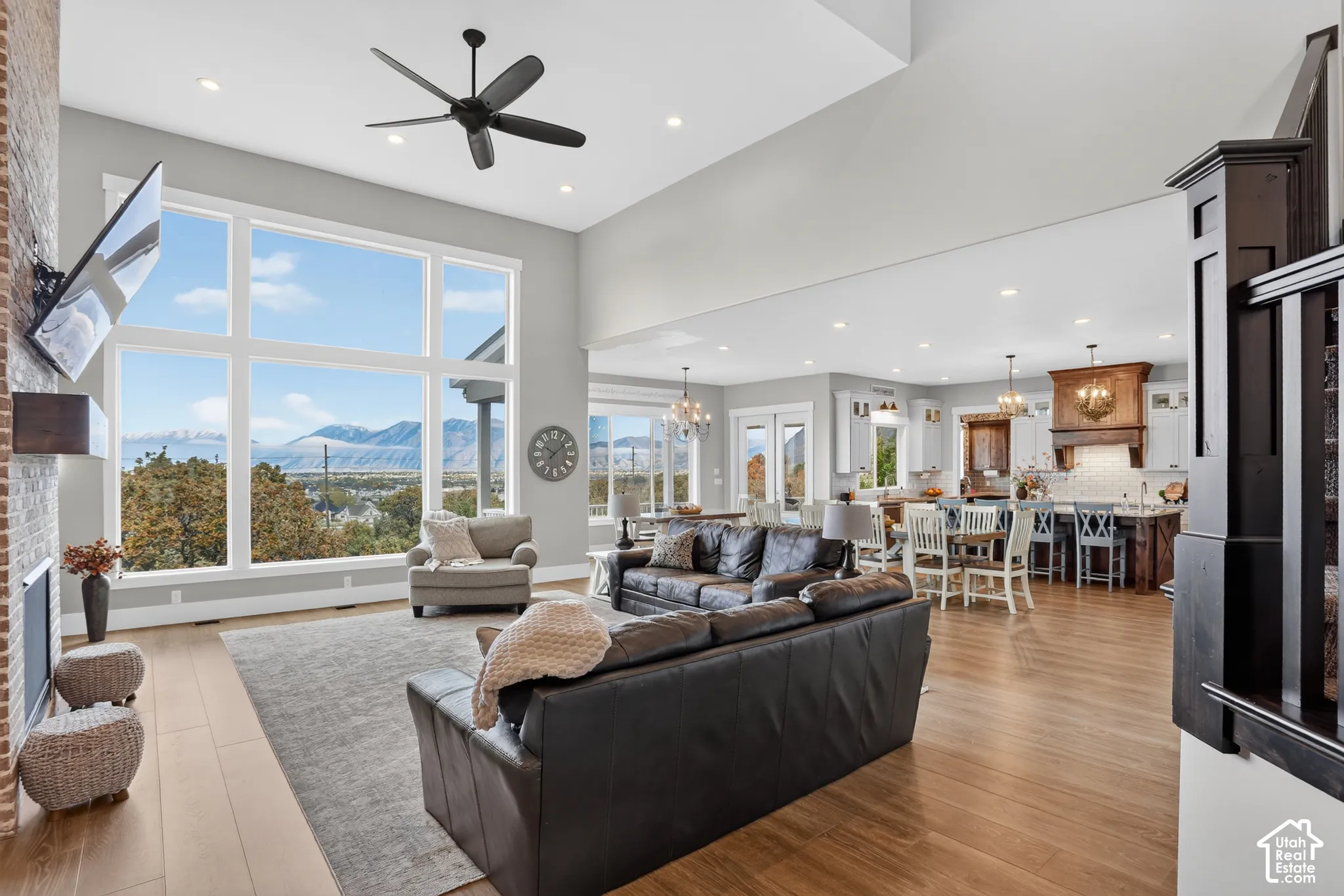 Vaulted ceilings, expansive floor-to-ceiling windows, mountain scenery, brick fireplace surround, and wood-finish flooring