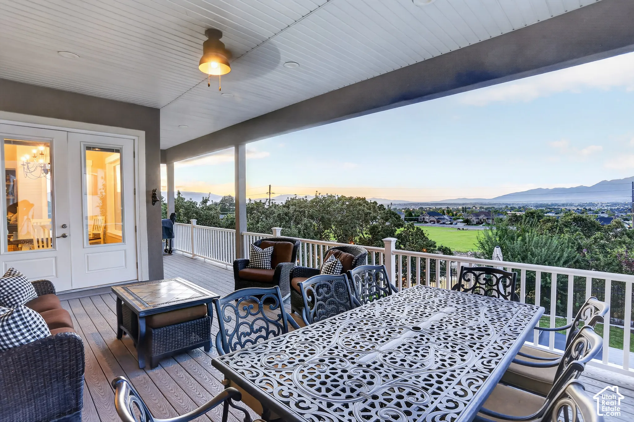 Covered outdoor deck featuring composite decking, white railing, ceiling-mounted lighting, and mountain scenery