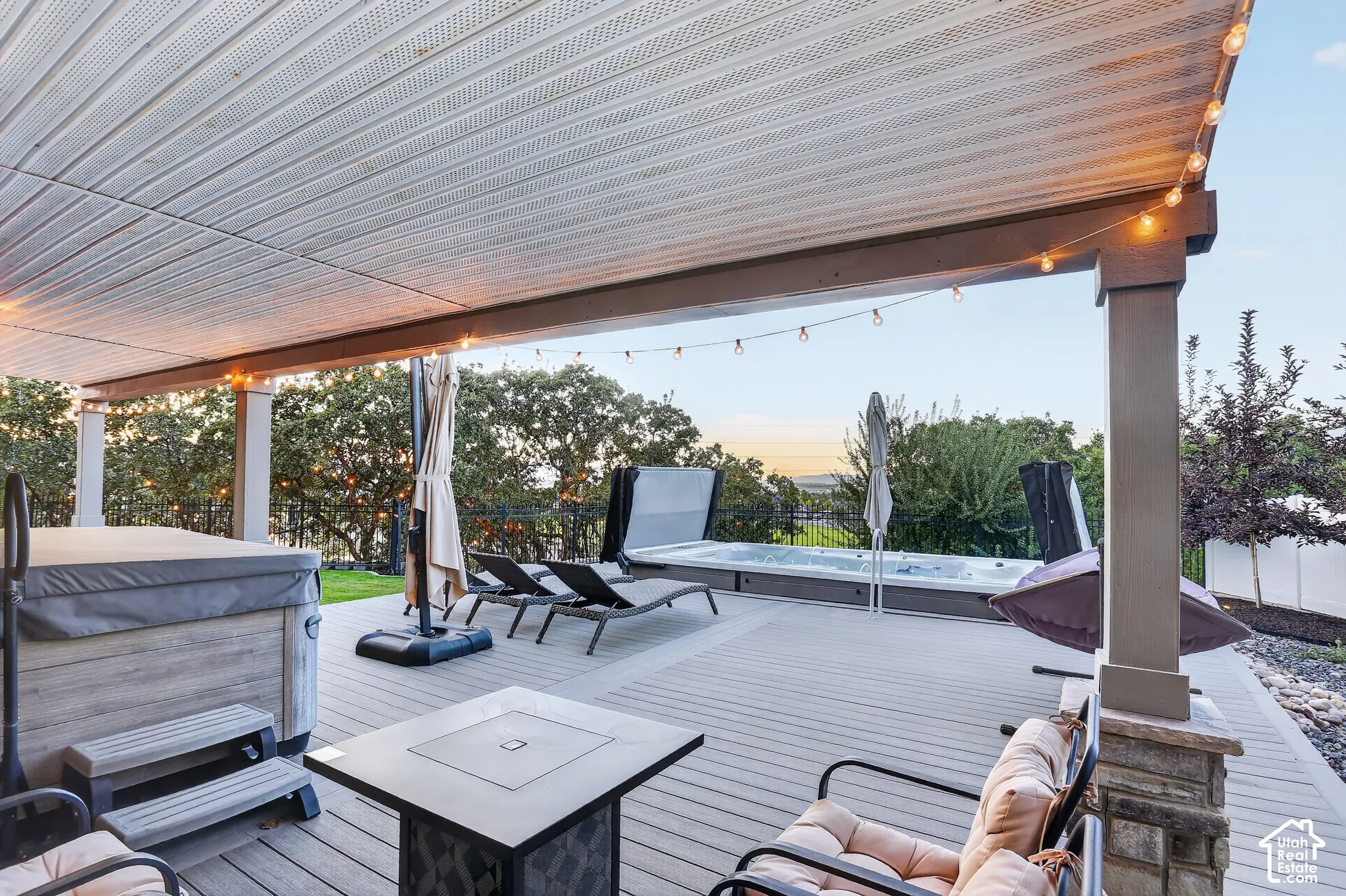 Covered composite deck featuring a built-in spa, stone-base structural columns, and an integrated lighting system