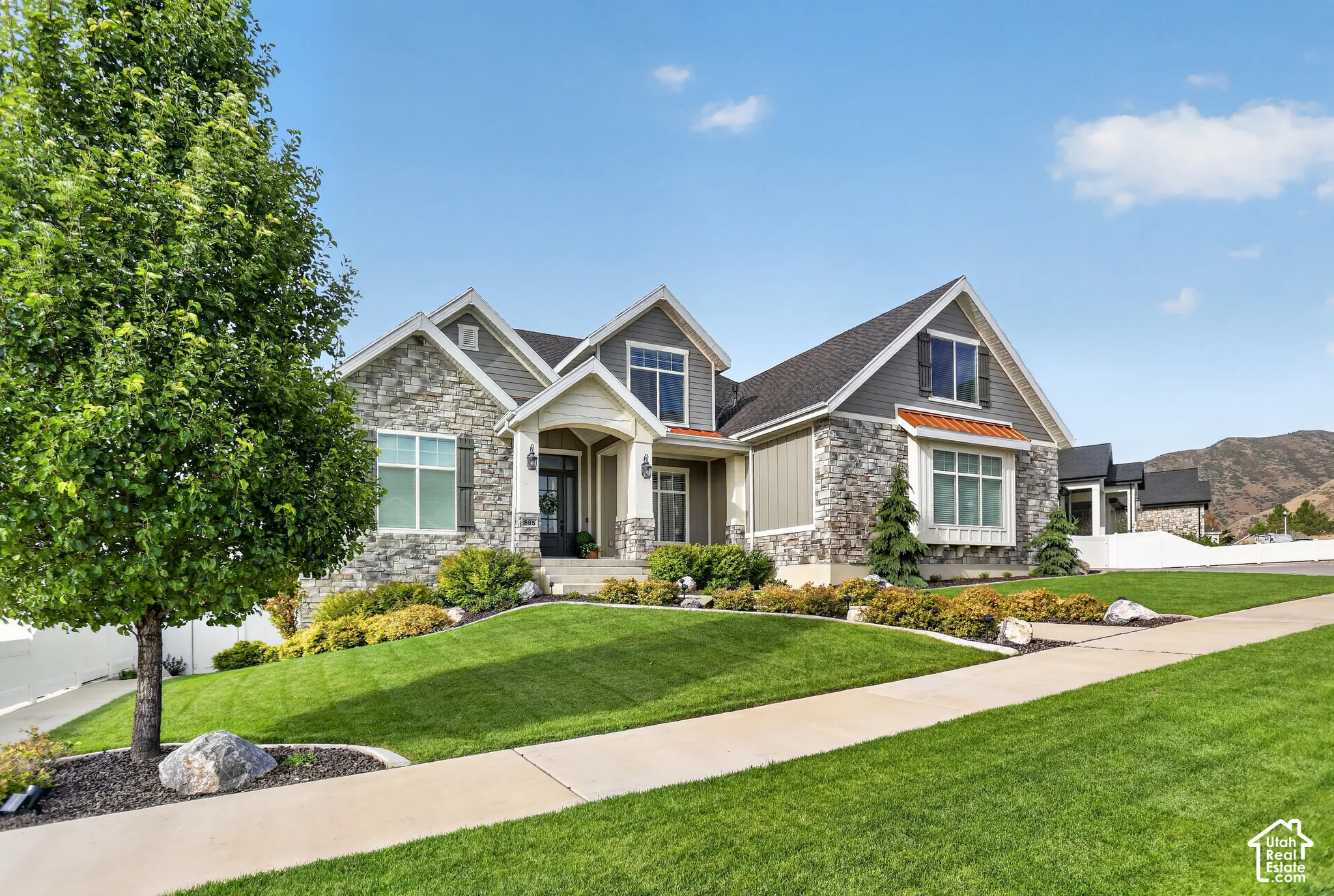 Multi-gabled exterior featuring stone veneer, horizontal and vertical siding, covered entryway with stone columns, and multi-pane windows