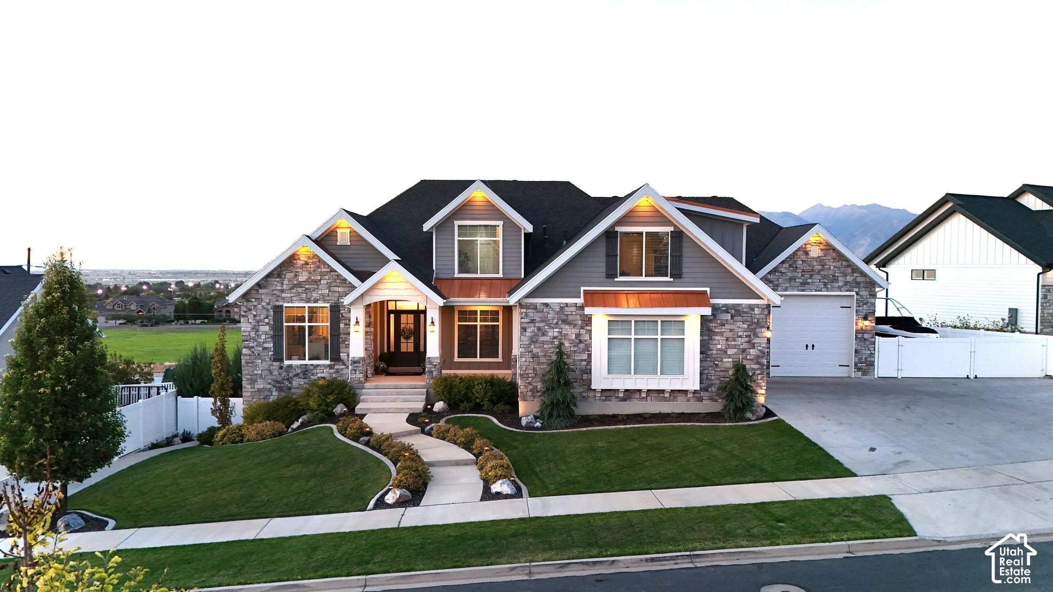 Multi-gabled exterior featuring stone veneer siding, horizontal lap siding, copper-toned metal roofing accents, and a paved walkway leading to the entrance