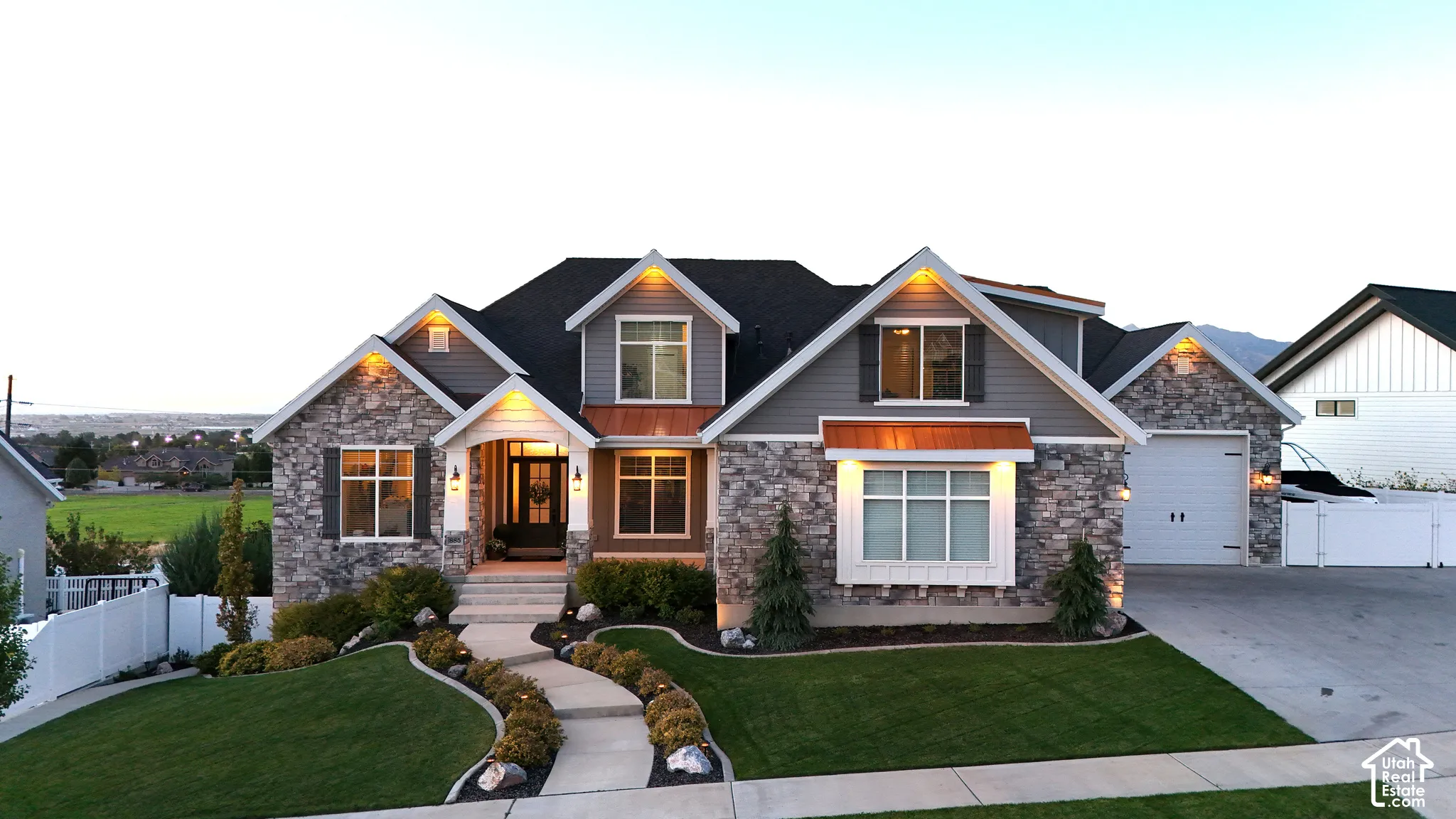Exterior featuring a stone and horizontal siding facade, copper-finish metal awnings, gabled rooflines, and a paved walkway leading to the entry
