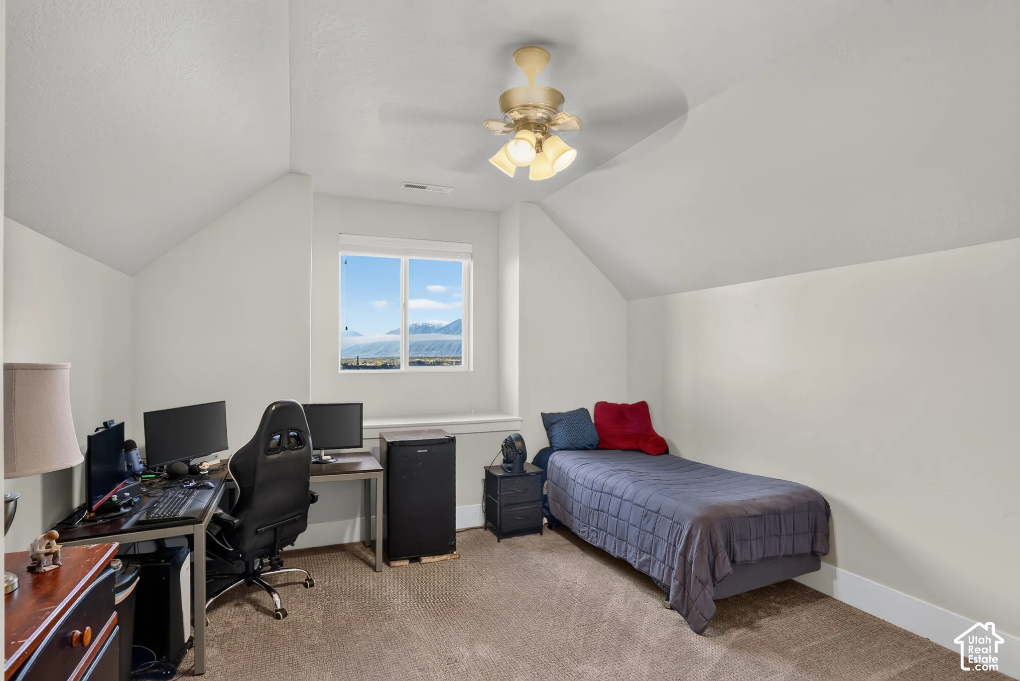 Vaulted ceilings, neutral wall palette, wall-to-wall carpeting, ceiling fan with multi-light fixture, and mountain scenery through the window