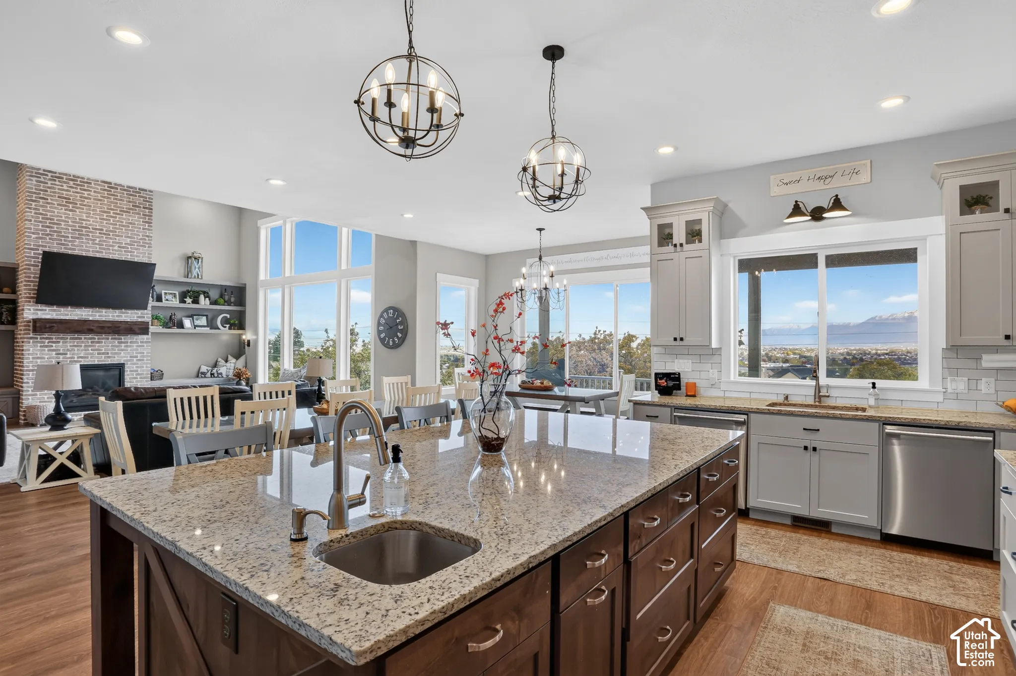 Kitchen featuring a large center island with a stone countertop and prep sink, shaker-style cabinetry, stainless steel appliances, and wood-finish flooring