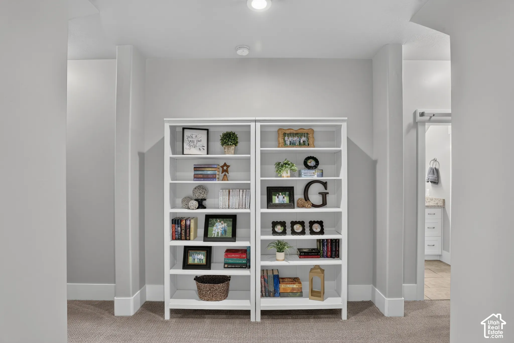 Built-in white shelving unit with multiple tiers and recessed ceiling lighting