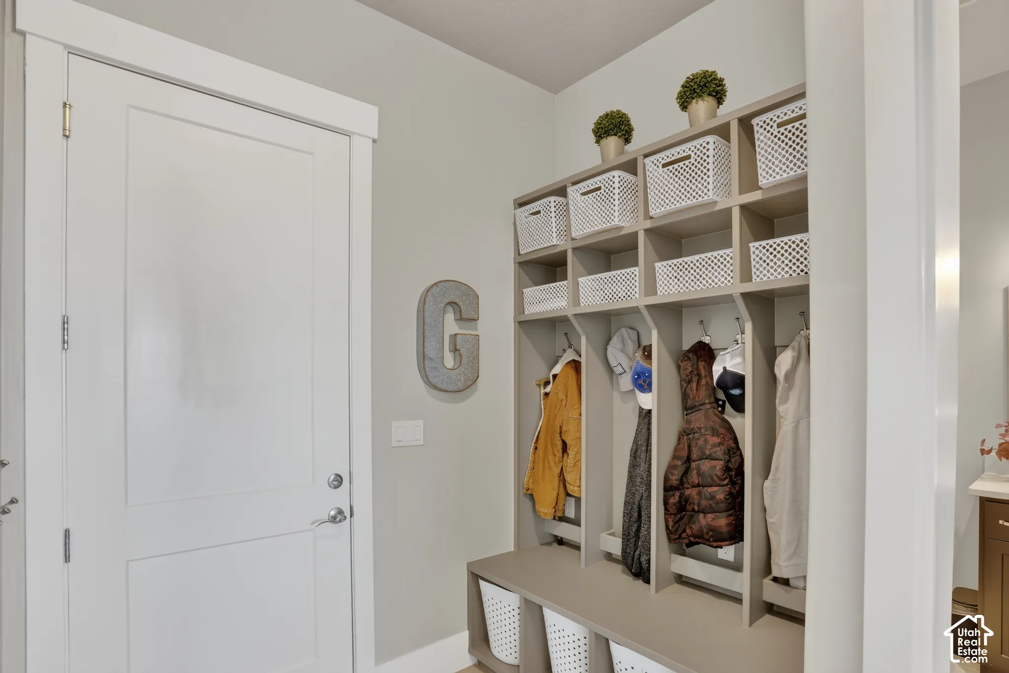 Built-in cabinetry featuring segmented upper cubbies, fixed coat hooks, and a bench with lower storage compartments