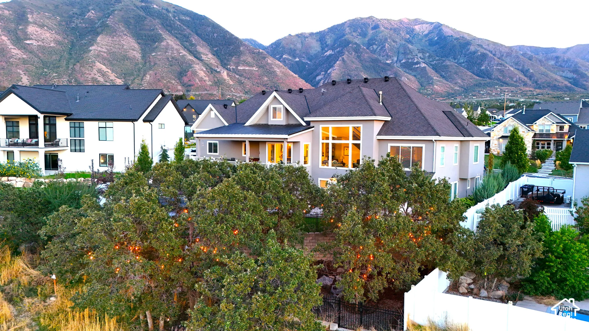 Multi-level residence featuring expansive mountain backdrops, high-pitched shingled rooflines, multi-pane windows, and a landscaped rear yard with mature trees