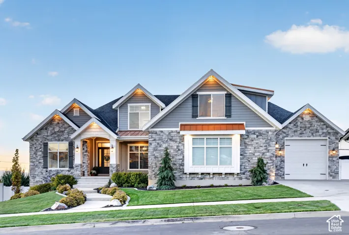 Multi-gabled exterior featuring stone veneer siding, horizontal lap siding, a metal roof accent over the bay window, and a concrete walkway