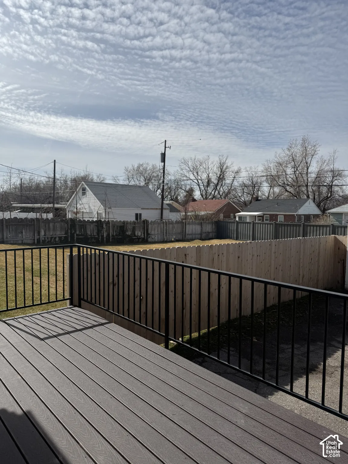 Elevated deck featuring composite decking and a black metal railing, overlooking a fenced backyard