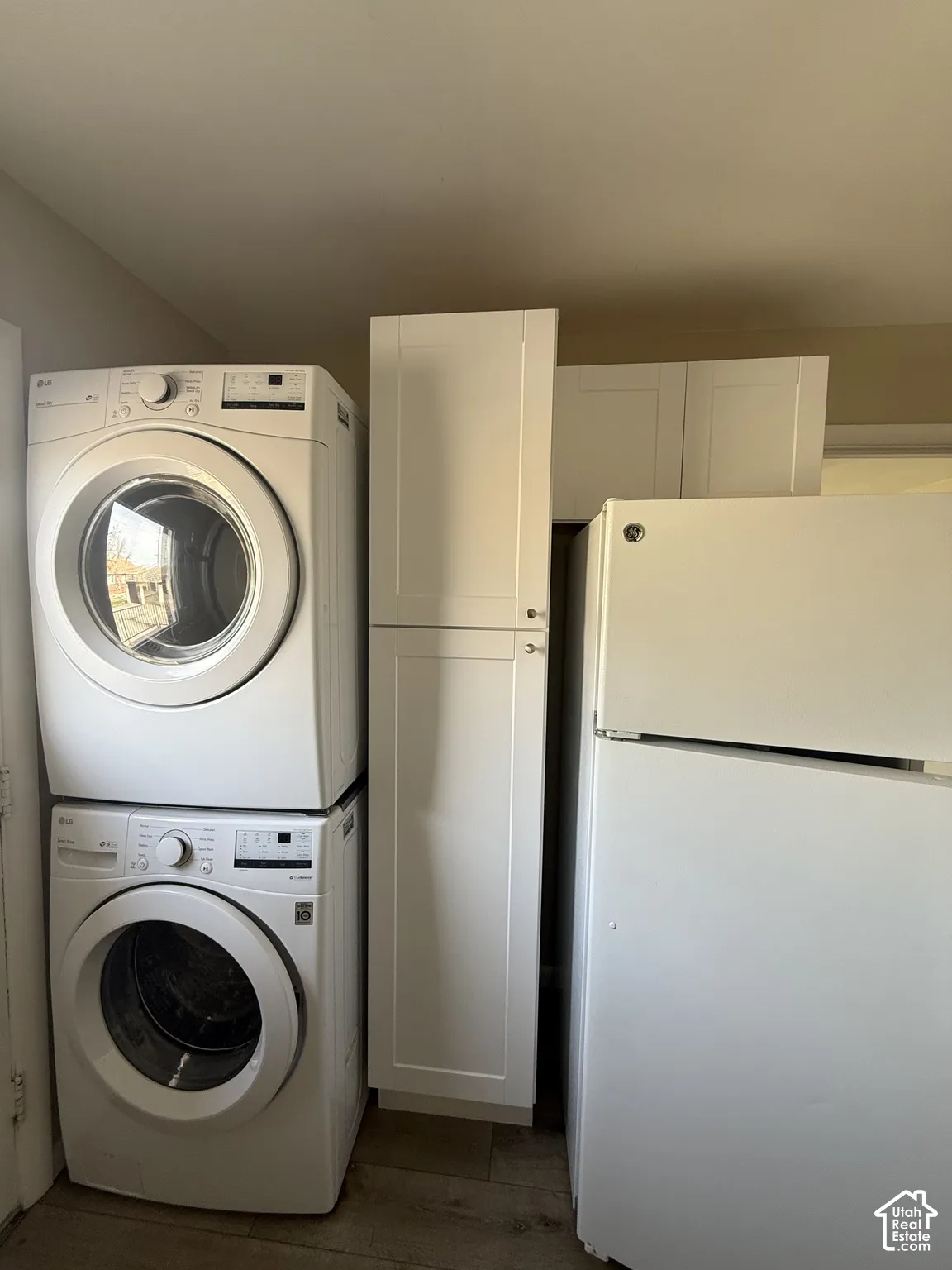 White shaker-style cabinetry with vertical storage pantry and wood-finish flooring