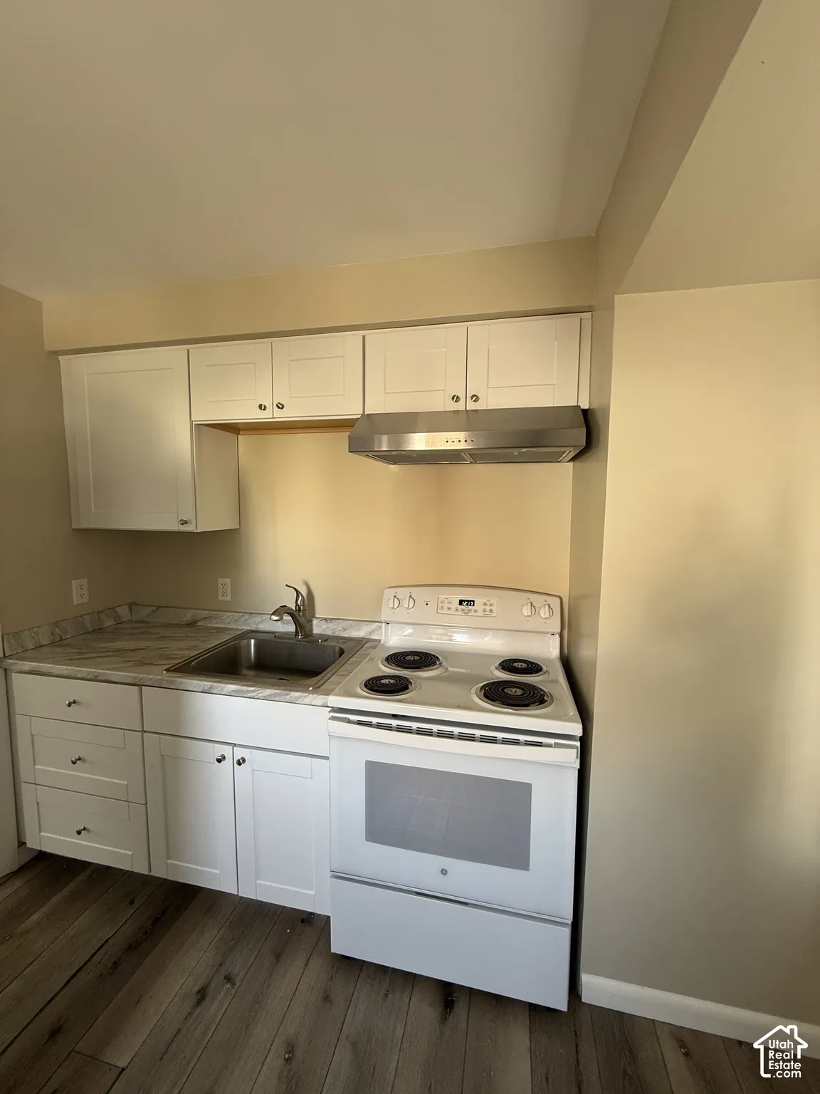 Kitchenette featuring white cabinetry, stone-finish countertops, stainless steel range hood, built-in electric range, and wood-finish flooring
