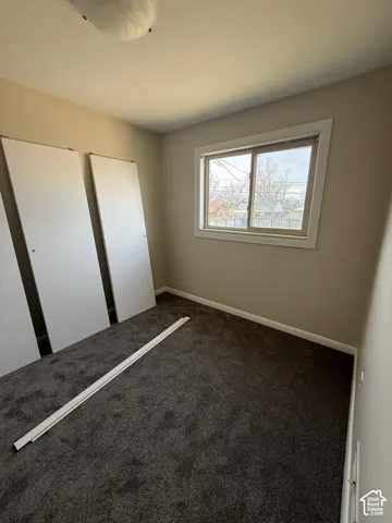 Room featuring neutral-toned walls, dark-toned carpeting, a sliding window, and two built-in closet doors